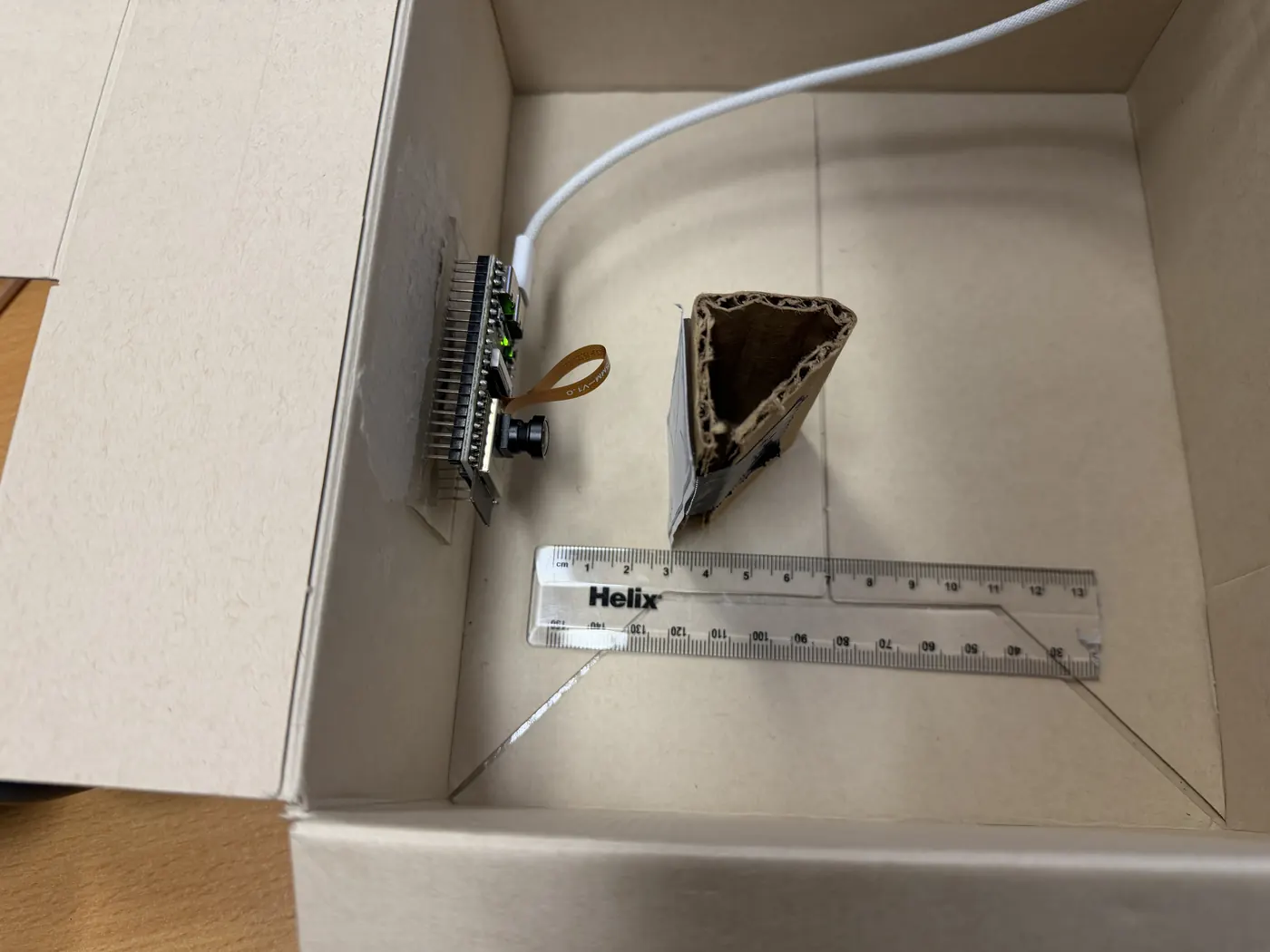 The focus test box with the ESP32 cam board on the side and a ruler on the floor