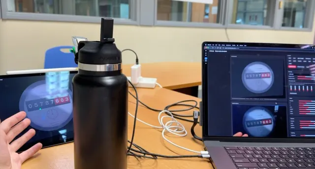 A tablet showing the MeterSim display next to a laptop with the control panel, with the ESP32-EYE reader pointed at the tablet